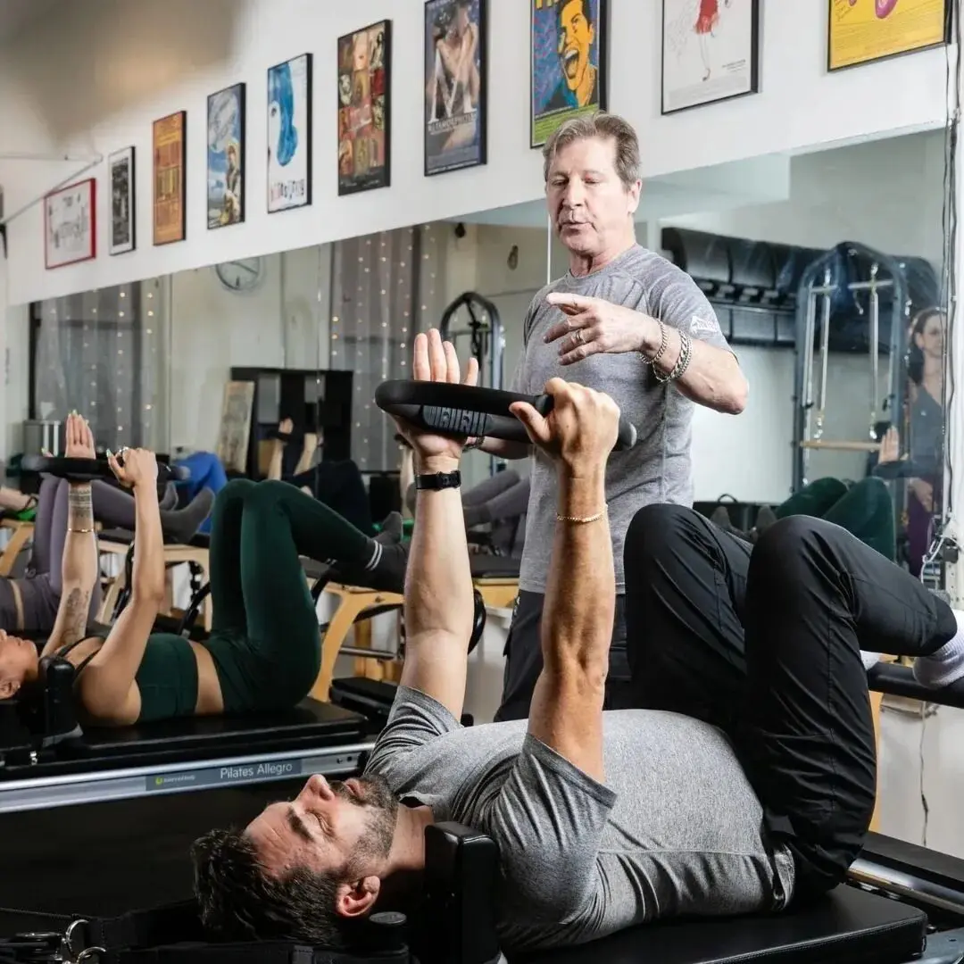 People exercising on Pilates reformer machines.