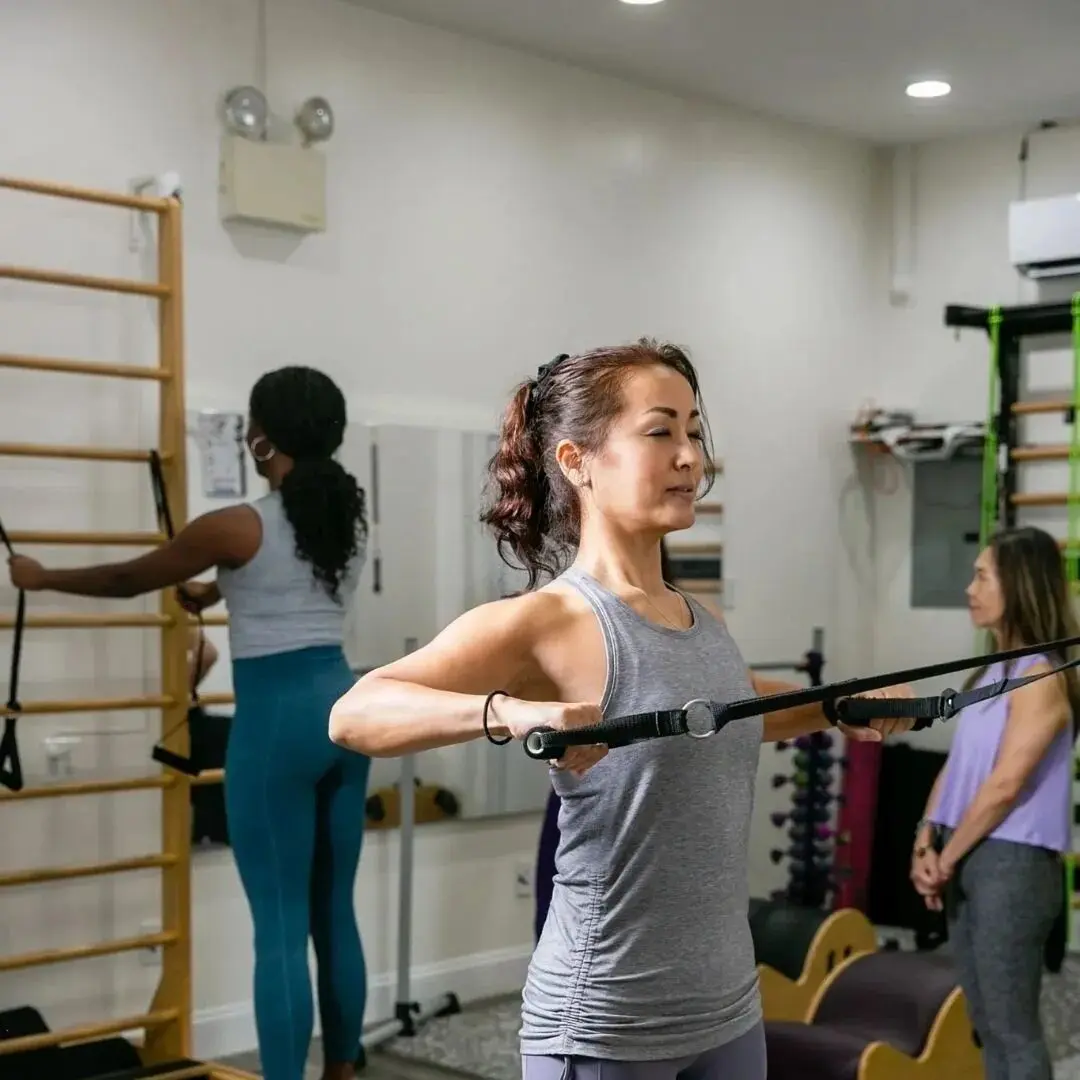 Women exercising with resistance bands in gym.
