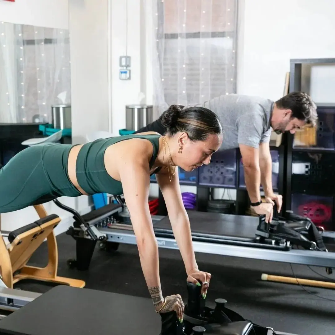 Two people exercising on Pilates reformers.